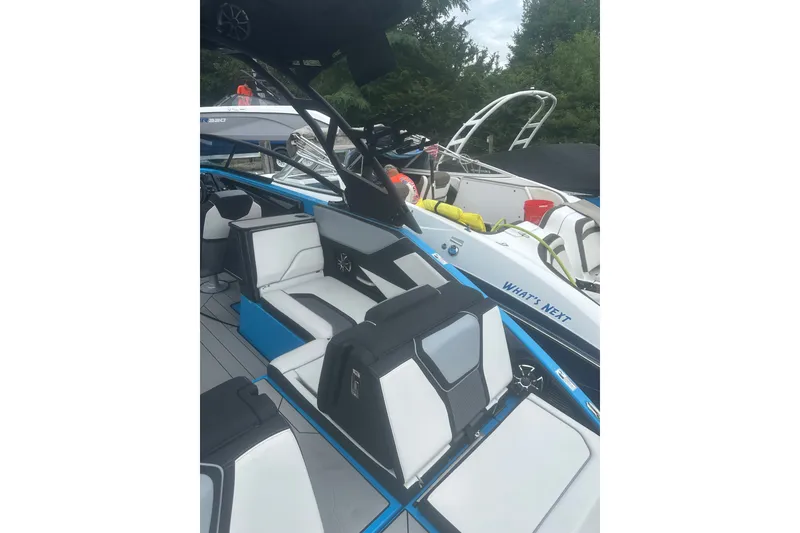 Slide: The Image of 2021 Yamaha Boats 255XE interior with sleek white and black seating, docked alongside other boats. - 10