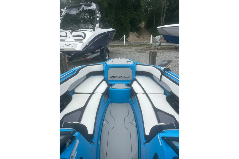 Slide: The Image of 2021 Yamaha Boats 255XE interior with blue and white seating, docked outdoors. - 15