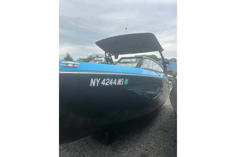Slide: The Image of 2021 Yamaha Boats 255XE in blue and black, parked on gravel. - 22