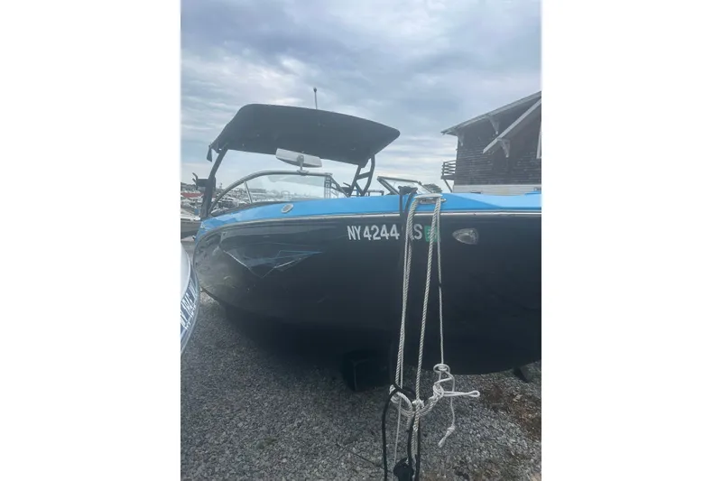 Slide: The Image of 2021 Yamaha Boats 255XE, black and blue, docked with ropes, cloudy sky background. - 21
