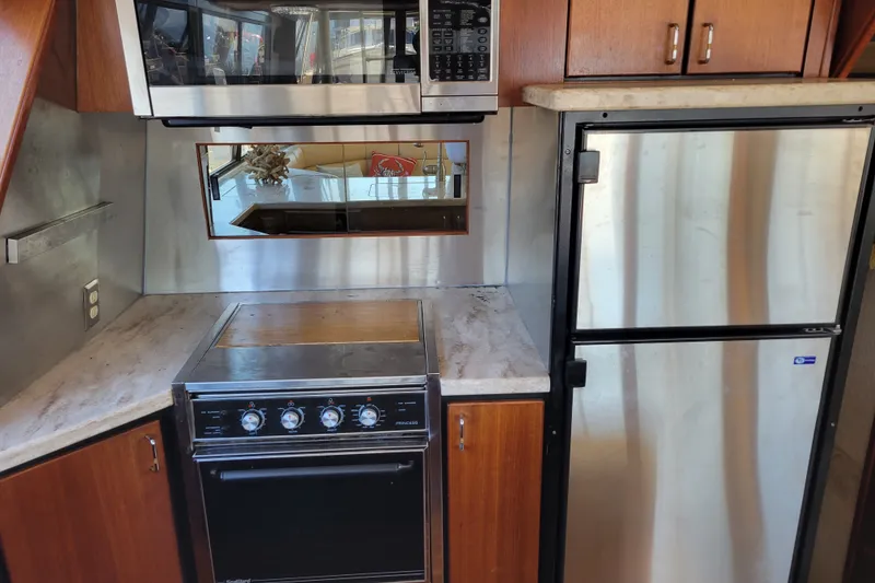 Slide: The Image of 1991 Bayliner 4588 Pilothouse kitchen with stove, microwave, and stainless steel refrigerator. - 14
