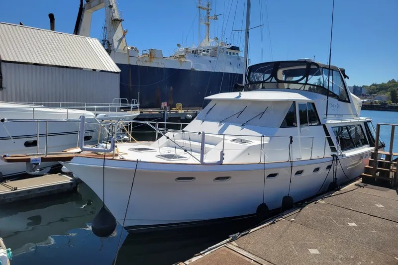 The Image of 1991 Bayliner 4588 Pilothouse yacht docked at marina under clear blue sky. - 1