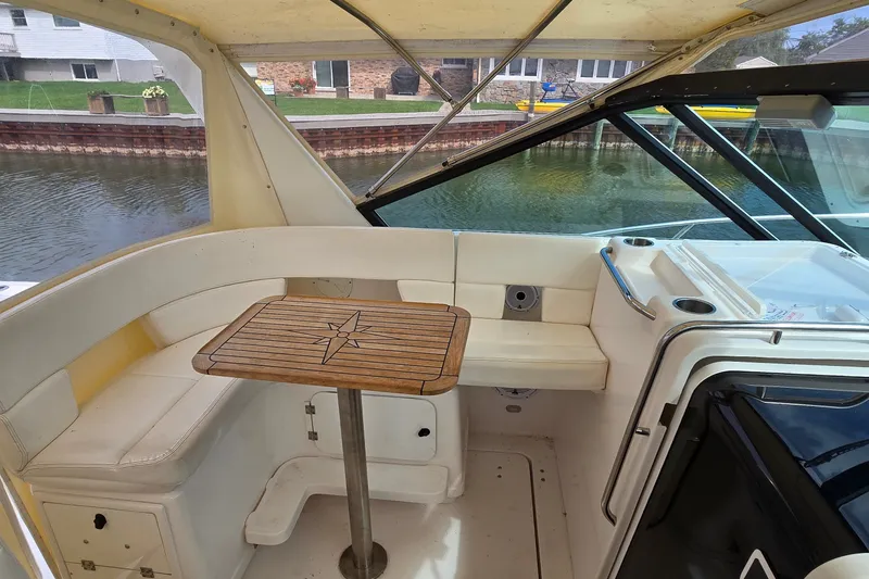 Slide: The Image of 2000 Tiara Yachts 3100 Open interior with seating and wooden table by the water. - 14