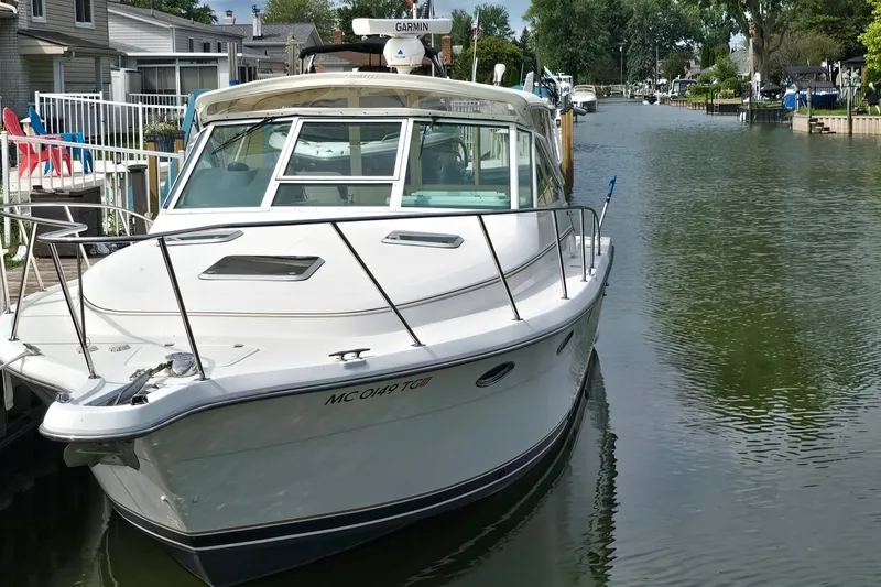 Slide: The Image of 2000 Tiara Yachts 3100 Open docked in a serene canal setting. - 3