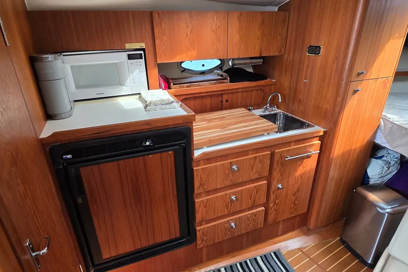 Slide: The Image of Compact kitchen area in a 2000 Tiara Yachts 3100 Open, featuring wood cabinetry and modern appliances. - 22