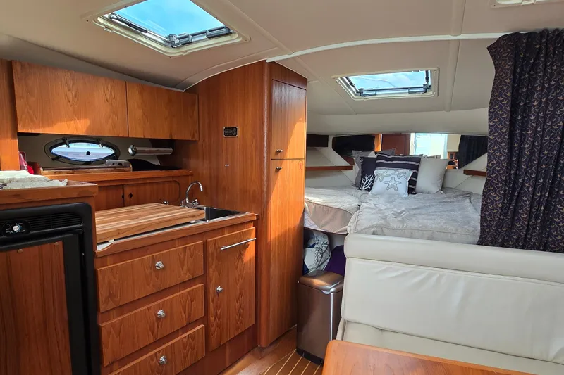 Slide: The Image of Interior of 2000 Tiara Yachts 3100 Open, featuring cozy cabin and kitchenette. - 17