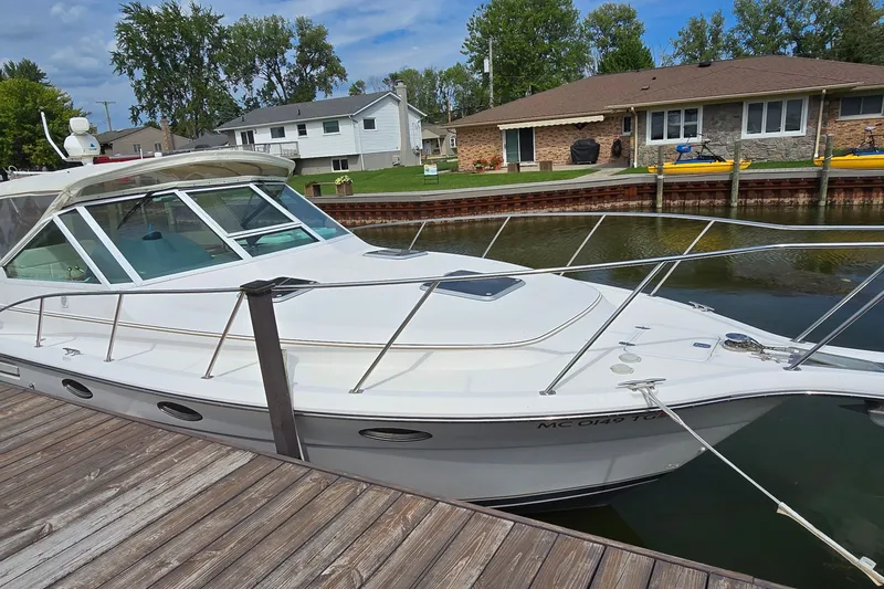 Slide: The Image of 2000 Tiara Yachts 3100 Open docked by waterfront homes, showcasing sleek design and spacious deck. - 2