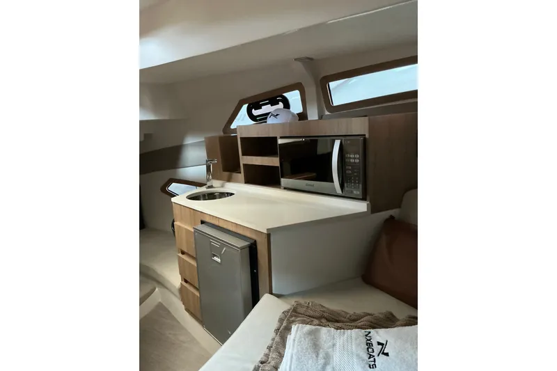 Slide: The Image of Modern kitchenette in 2027 NX Boats 350 Maximus, featuring microwave and compact sink. - 20