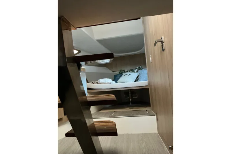 Slide: The Image of Interior cabin of 2027 NX Boats 350 Maximus, featuring cozy bedding and wooden stairs. - 23