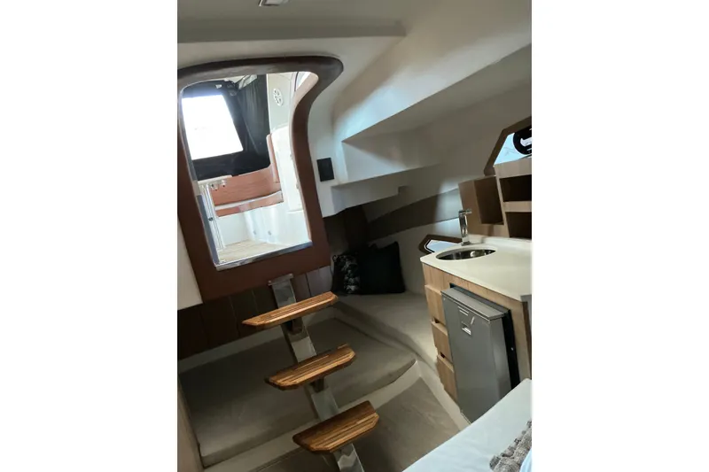 Slide: The Image of Interior of 2027 NX Boats 350 Maximus, featuring modern kitchenette and wooden steps. - 21