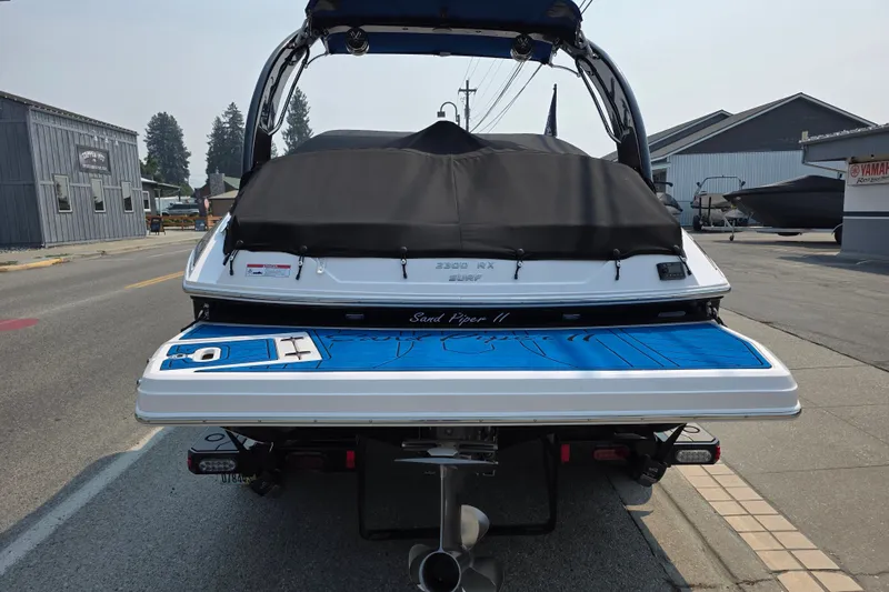 Slide: The Image of 2018 Regal 2300 RX Surf boat with covered deck, parked on street. - 2