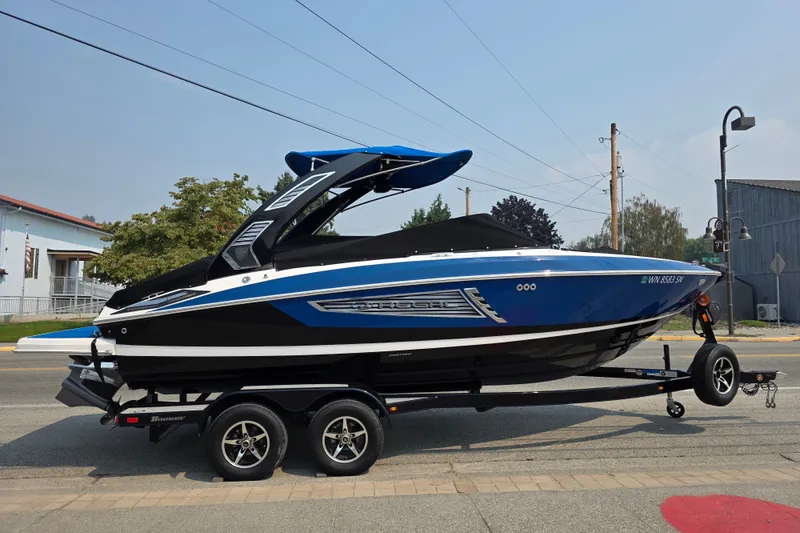 Slide: The Image of 2018 Regal 2300 RX Surf boat on trailer, parked on street. - 1
