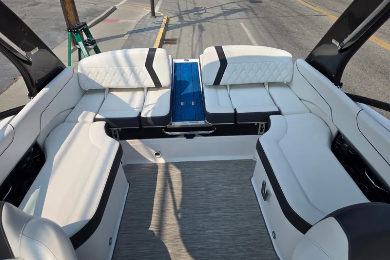 Slide: The Image of Interior of a 2018 Regal 2300 RX Surf boat with white seating and blue accents. - 8