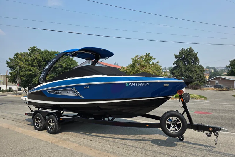 The Image of 2018 Regal 2300 RX Surf boat on trailer, parked on street. - 0