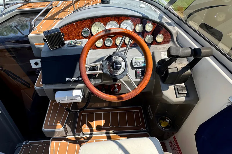 Slide: The Image of 2010 Regal 2860 Window Express boat dashboard with wooden steering wheel and control panel. - 6