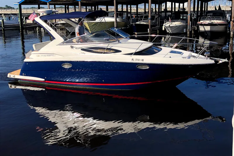 Slide: The Image of 2010 Regal 2860 Window Express boat docked in marina, reflecting on calm water. - 1