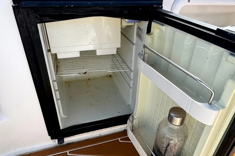 Slide: The Image of Open mini fridge on 2010 Regal 2860 Window Express boat, showing interior shelves and bottle. - 12