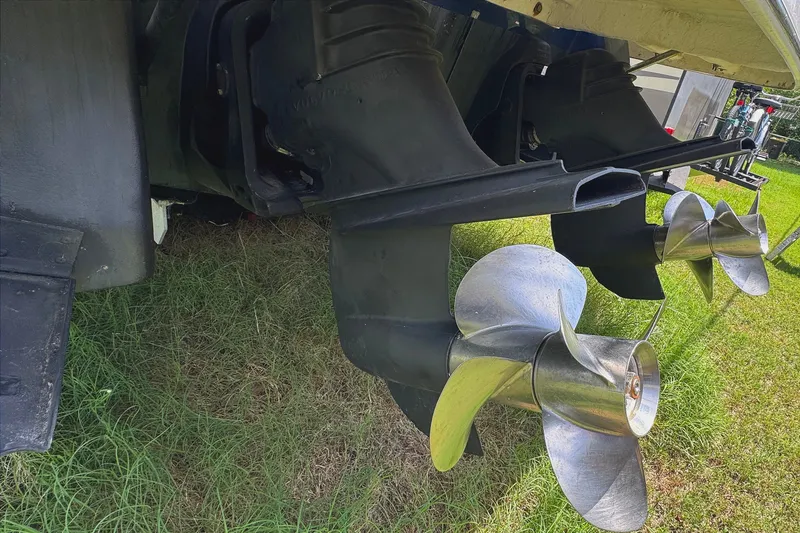 Slide: The Image of 2010 Regal 2860 Window Express boat propellers on grass, showcasing dual outdrives. - 5