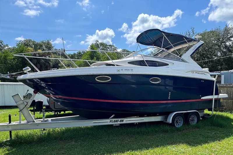 Slide: The Image of 2010 Regal 2860 Window Express boat on trailer, parked on grass under blue sky. - 2