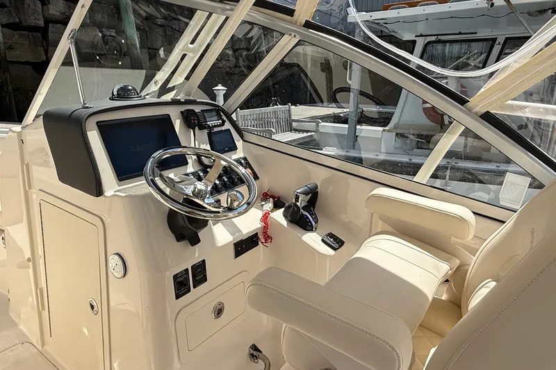 Slide: The Image of 2024 Grady-White Freedom 255 boat cockpit with steering wheel and navigation controls. - 3