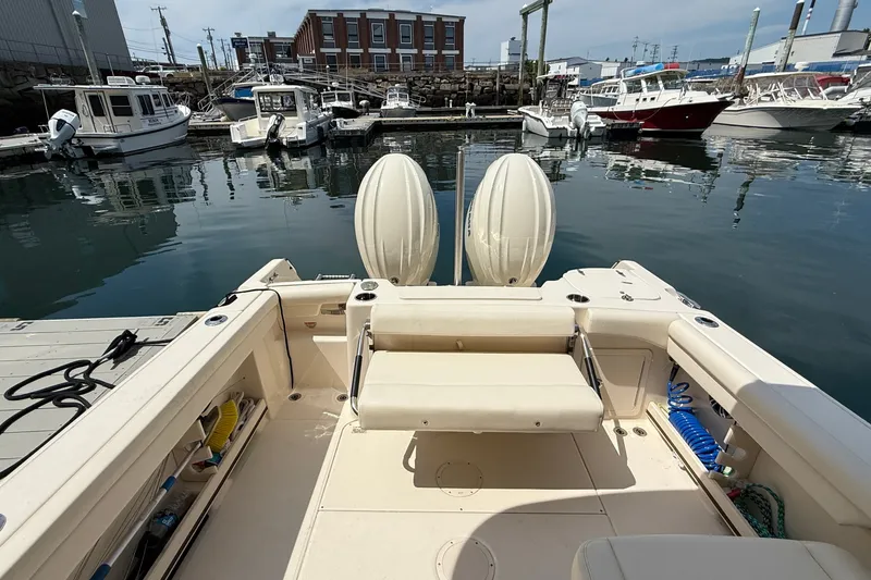 Slide: The Image of 2024 Grady-White Freedom 255 boat docked in a marina, showcasing spacious seating and twin engines. - 10