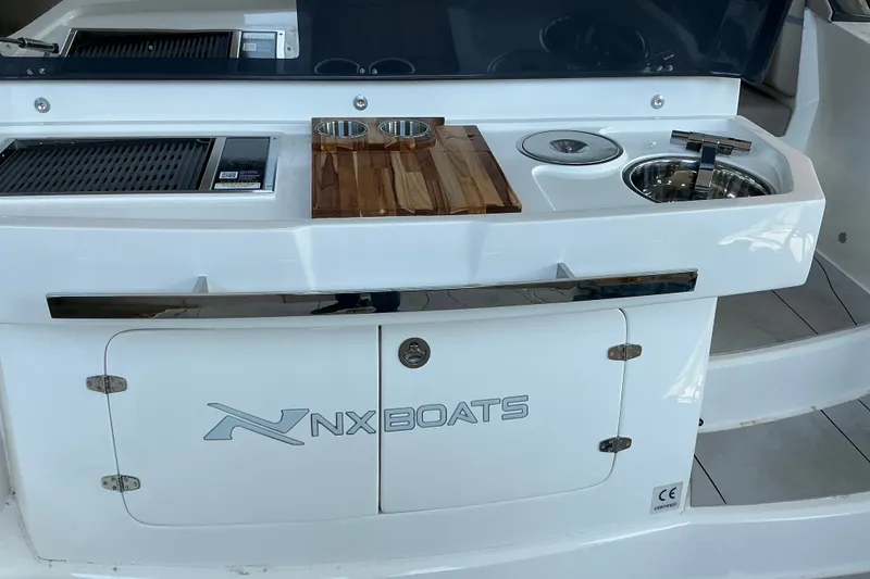 Slide: The Image of Outdoor kitchen on 2027 NX Boats 41 Horizon, featuring grill, sink, and cutting board. - 14