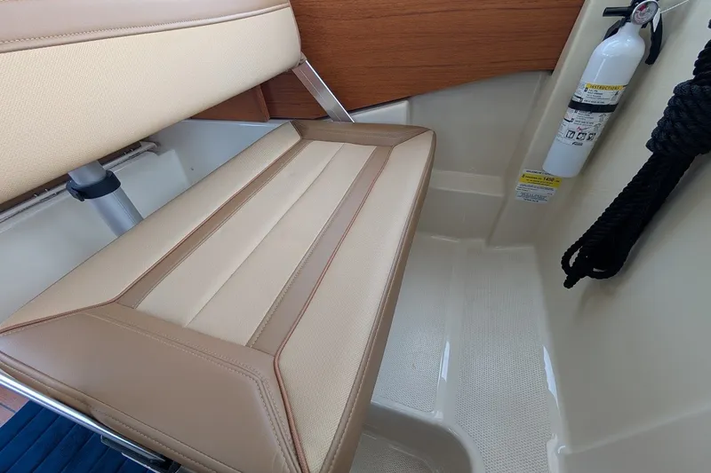 Slide: The Image of 2023 Ranger Tugs interior with beige seating, fire extinguisher, and black rope. - 19