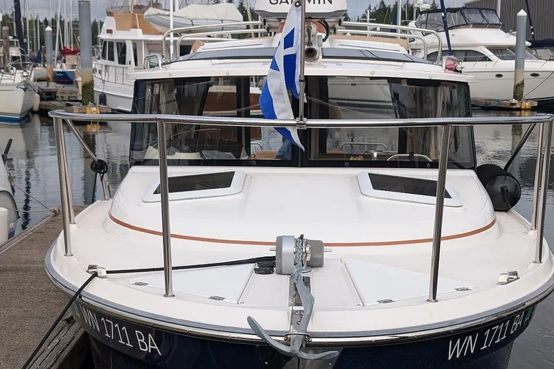 Slide: The Image of 2023 Ranger Tugs boat docked at marina with flag and railing. - 1