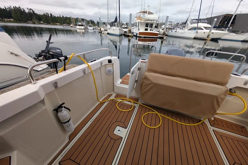 Slide: The Image of 2023 Ranger Tugs boat interior with teak flooring, docked at a marina. - 23