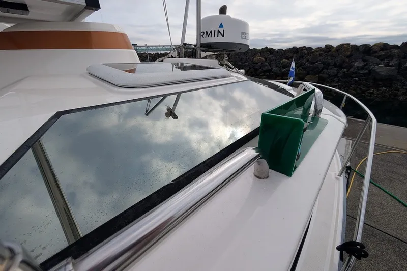 Slide: The Image of 2023 Ranger Tugs boat with reflective windows and Garmin radar, docked near rocky shoreline. - 29