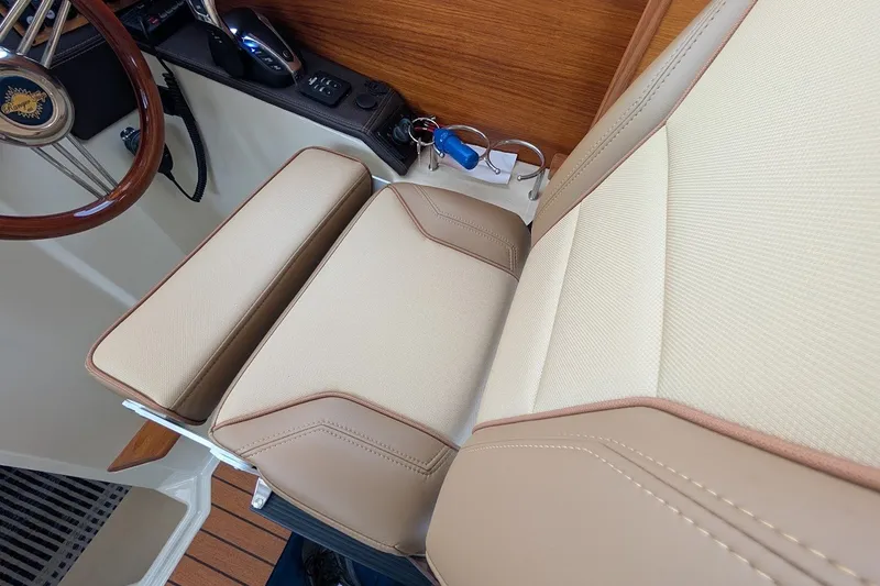 Slide: The Image of 2023 Ranger Tugs boat interior with beige leather seating and wooden steering wheel. - 18