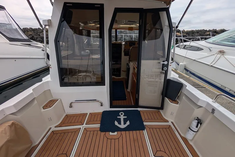 Slide: The Image of 2023 Ranger Tugs boat interior with teak flooring and glass doors at a marina. - 32