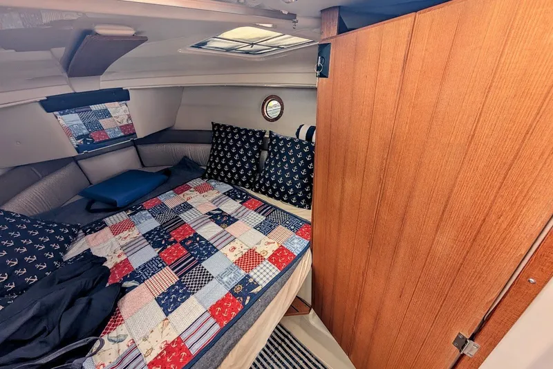 Slide: The Image of 2023 Ranger Tugs cabin interior with nautical-themed bedding and wooden door. - 9