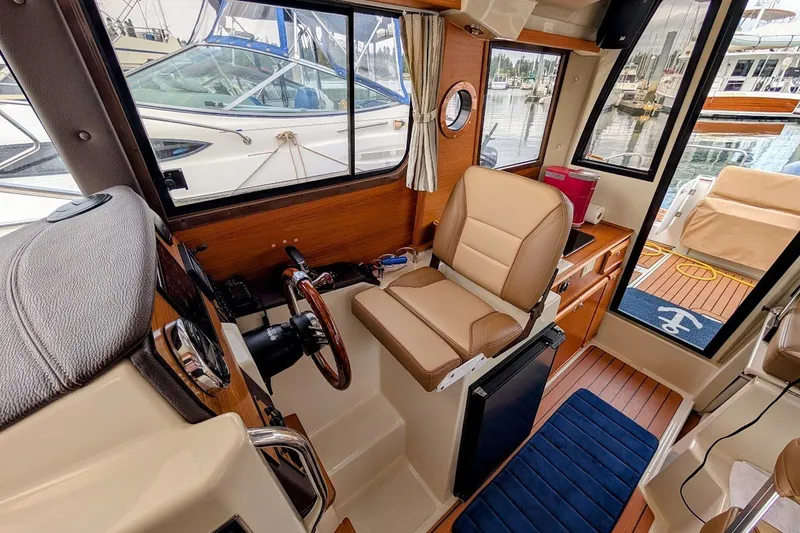 Slide: The Image of Interior of a 2023 Ranger Tugs boat with helm, seating, and marina view. - 5