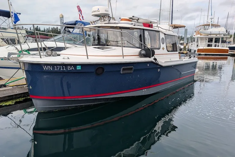 The Image of 2023 Ranger Tugs boat docked in marina, featuring blue hull and red stripe. - 0