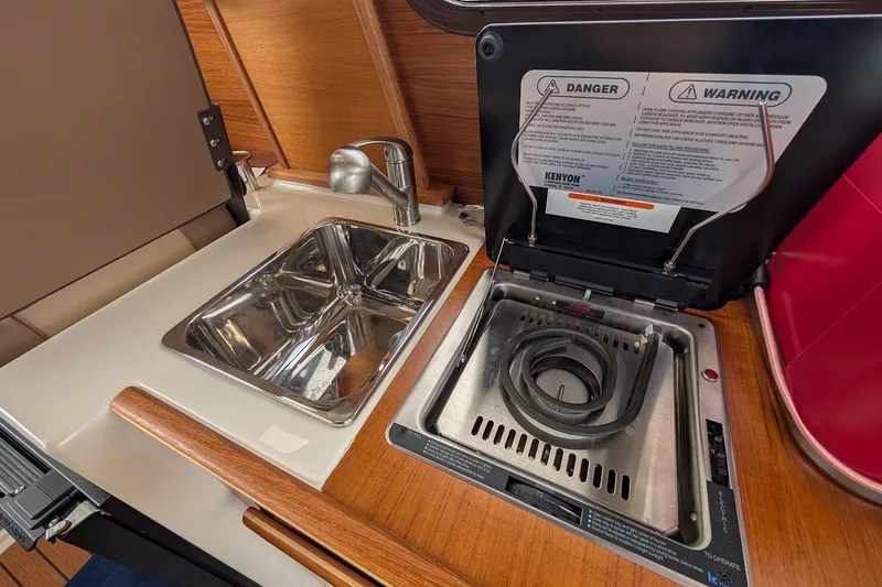 Slide: The Image of 2023 Ranger Tugs boat kitchen with stainless steel sink and electric stove. - 14