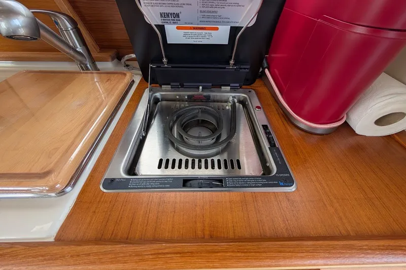 Slide: The Image of 2023 Ranger Tugs kitchen with Kenyon electric stove, wooden countertop, and sink. - 13