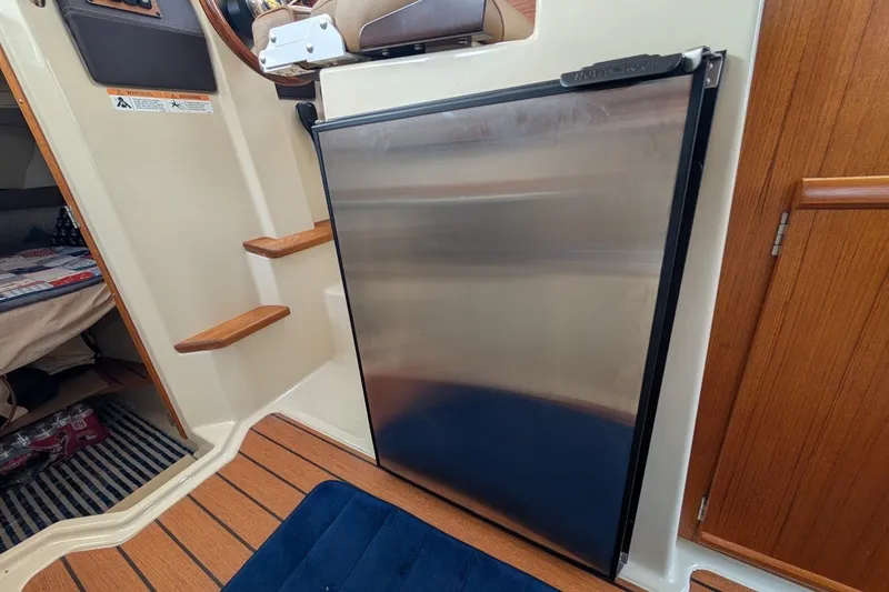 Slide: The Image of 2023 Ranger Tugs interior with stainless steel fridge and wooden steps. - 15