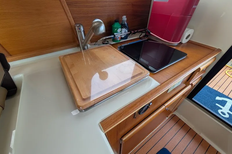 Slide: The Image of 2023 Ranger Tugs boat kitchen with sink, cutting board, and tablet on wooden counter. - 12