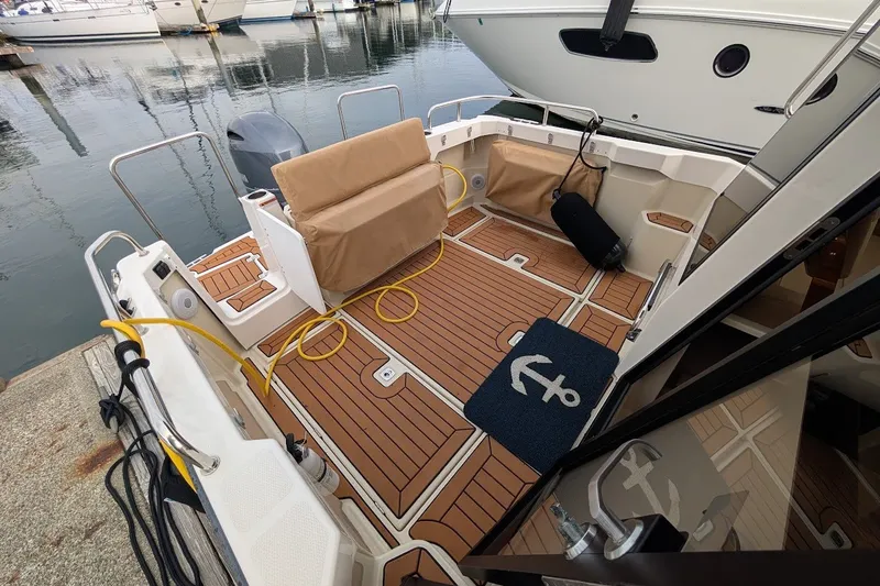Slide: The Image of 2023 Ranger Tugs boat deck with teak flooring and anchor-themed mat at marina. - 35