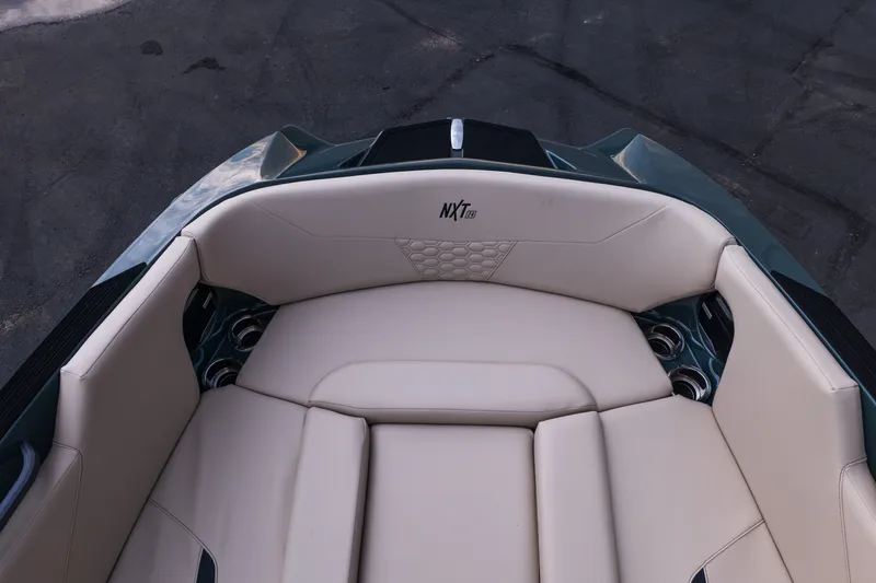 Slide: The Image of 2027 MasterCraft NXT24 boat interior with beige seating and cup holders. - 24