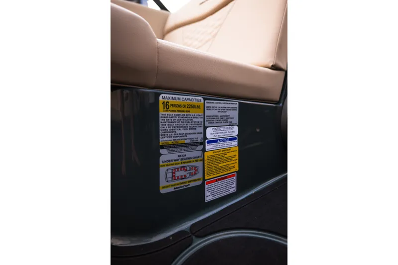 Slide: The Image of 2027 MasterCraft NXT24 boat capacity label, seating for 16, beige upholstery detail. - 34