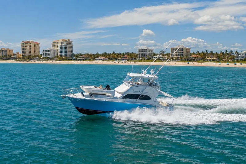 Slide: The Image of 2005 Riviera 51 Flybridge cruising on blue ocean near beachfront cityscape. - 2