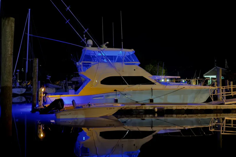 Slide: The Image of 2005 Riviera 51 Flybridge yacht illuminated at night, docked with reflections on water. - 4