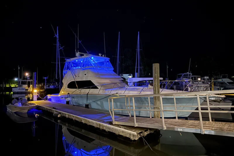 Slide: The Image of 2005 Riviera 51 Flybridge yacht illuminated at night in a marina. - 5
