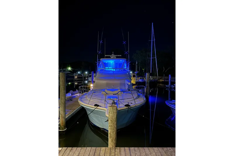 Slide: The Image of 2005 Riviera 51 Flybridge yacht illuminated at night in a marina. - 3