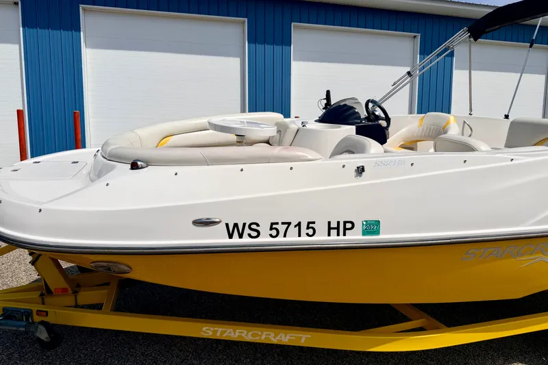 Slide: The Image of 2008 Starcraft Aurora Star Step 190 IO boat on yellow trailer, parked near blue building. - 12