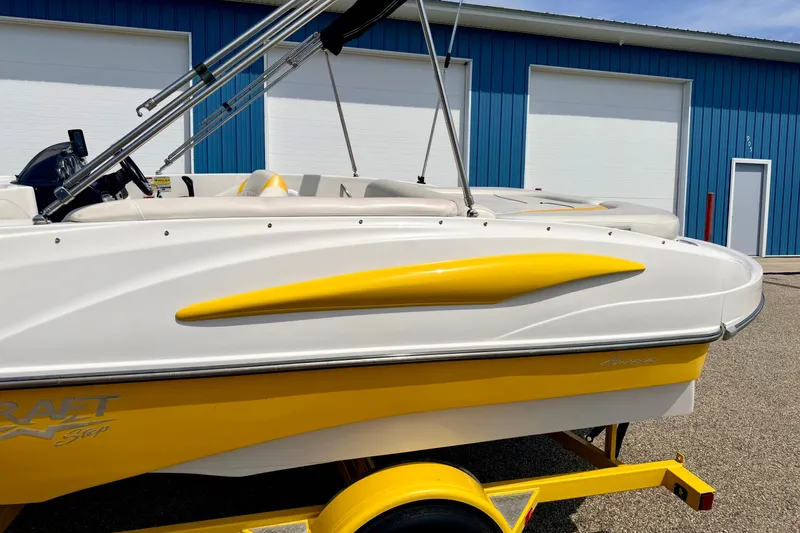 Slide: The Image of 2008 Starcraft Aurora Star Step 190 IO boat with yellow accents, parked near blue building. - 11