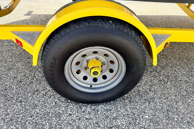 Slide: The Image of Yellow trailer wheel of 2008 Starcraft Aurora Star Step 190 IO on asphalt. - 86