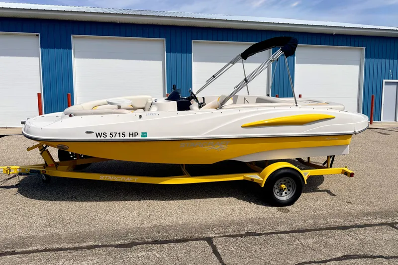 Slide: The Image of 2008 Starcraft Aurora Star Step 190 IO boat on yellow trailer, parked outside blue building. - 1